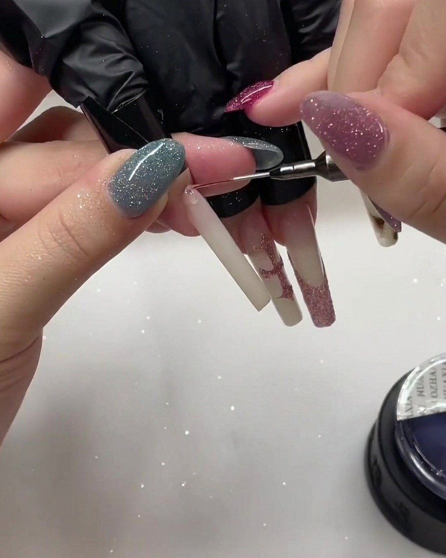 Ein Nagel, der mit zusätzlicher Glitzerpartikeln mittels eines Detailpinsels geschichtet wird.
