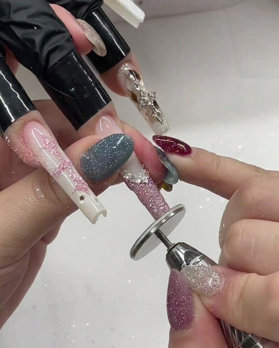 Ein Pinsel trägt feinen rosa Glitzer auf eine weiße French-Tip-Gelspitze auf.
