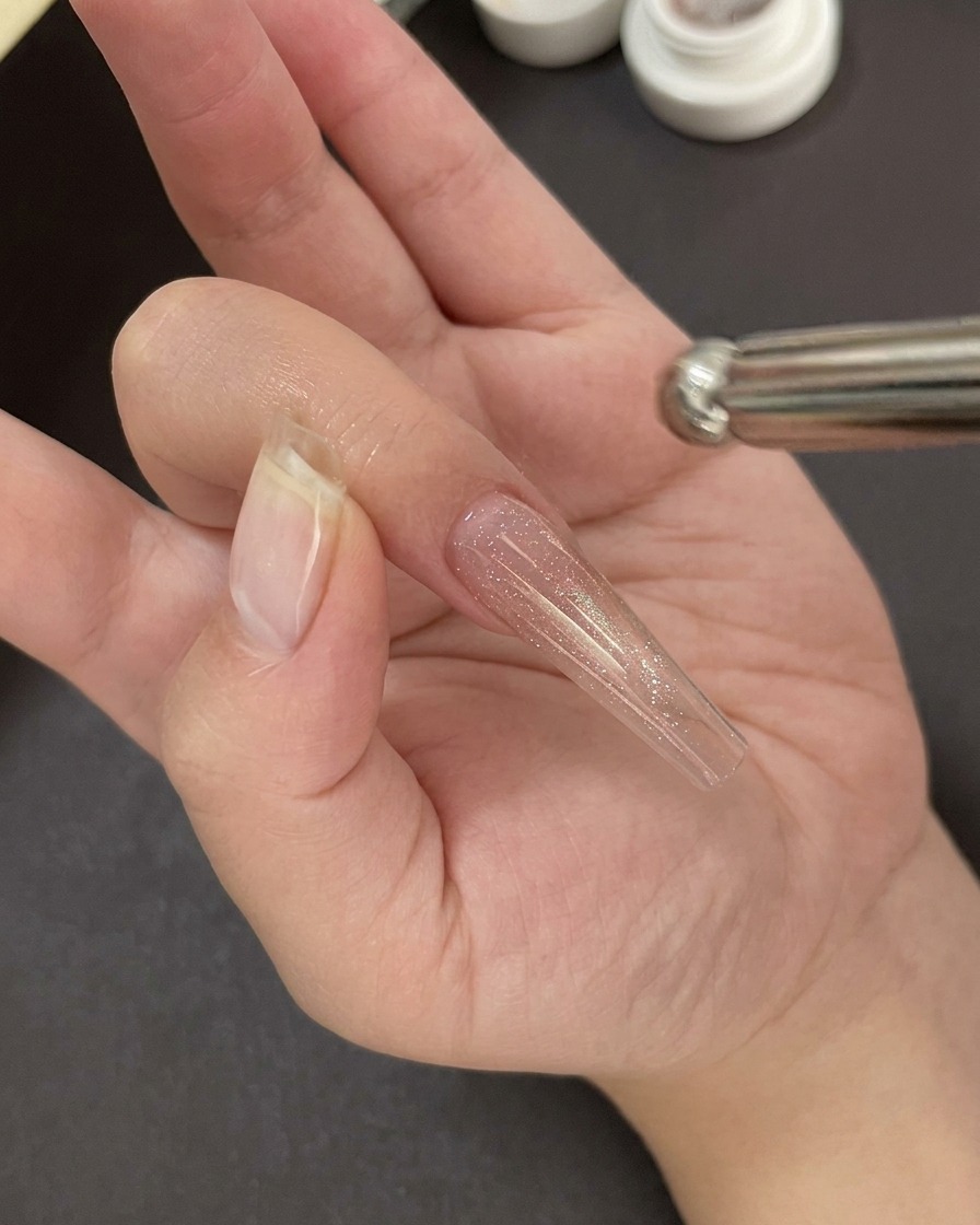 Eine Hand unter einer professionellen UV/LED-Nagellampe beim Aushärten der Gel-Basisschicht.