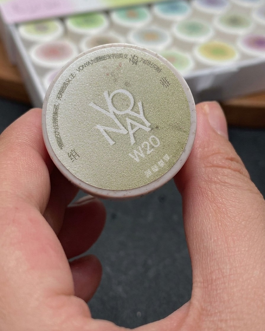 Ein Pinsel trägt ein schimmerndes weißes Cat-Eye-Gel gleichmäßig auf die gesamte Nageloberfläche auf.