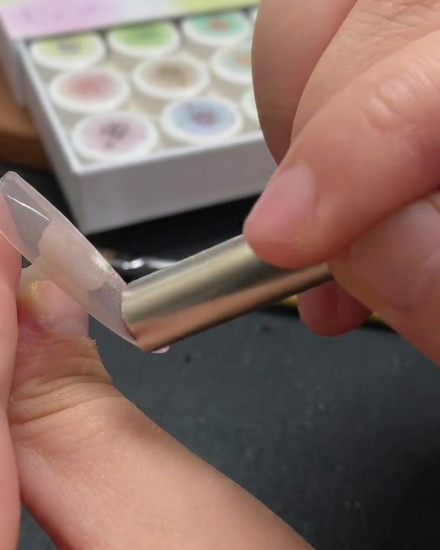 Ein Fingernagel unter dem violetten Licht einer UV/LED-Lampe, das das Cat-Eye-Design fixiert.