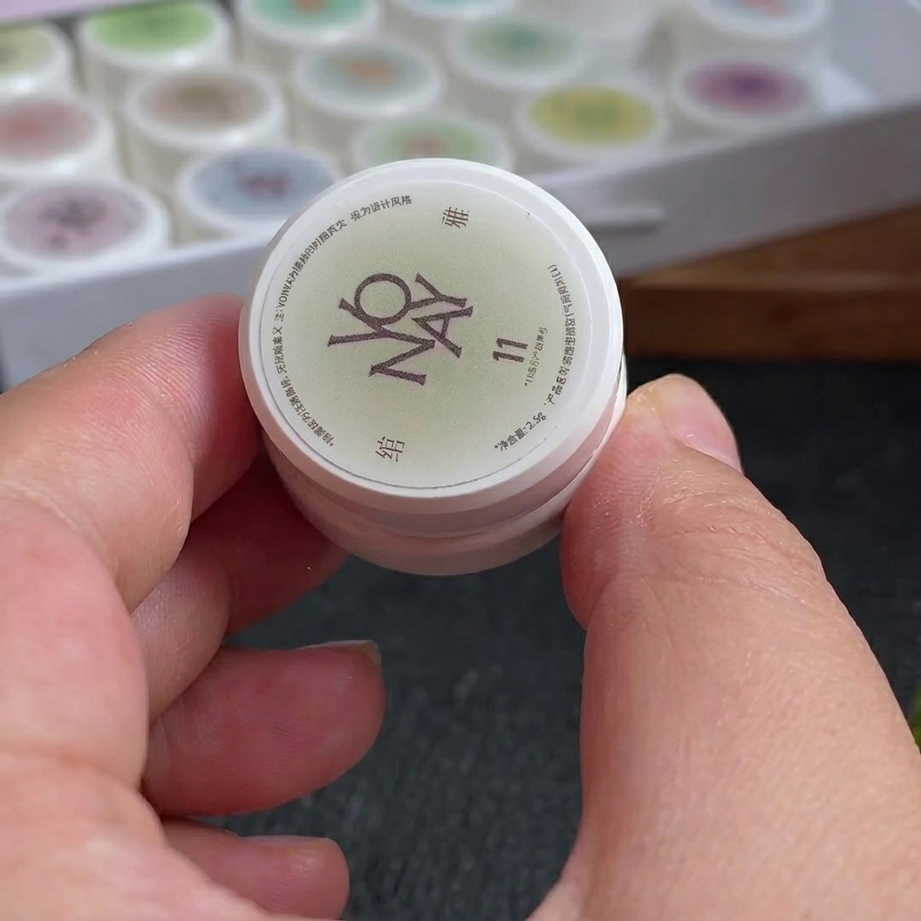 Ein kleiner Make-up-Schwamm mit Linien aus weißem und rosarotem Gel-Nagellack auf seiner Oberfläche.