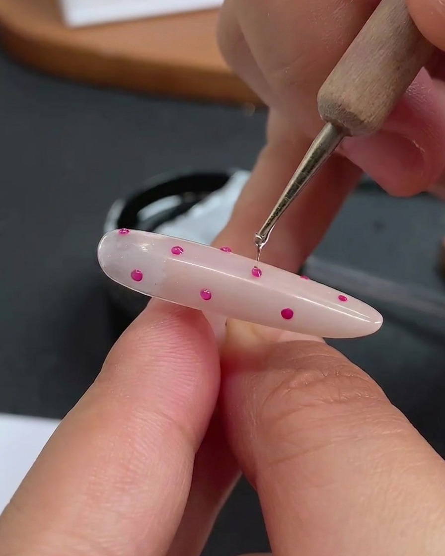 Ein Dotting-Tool trägt einen kleinen, klaren Tropfen Hartgel über jeden einzelnen Punkt auf.