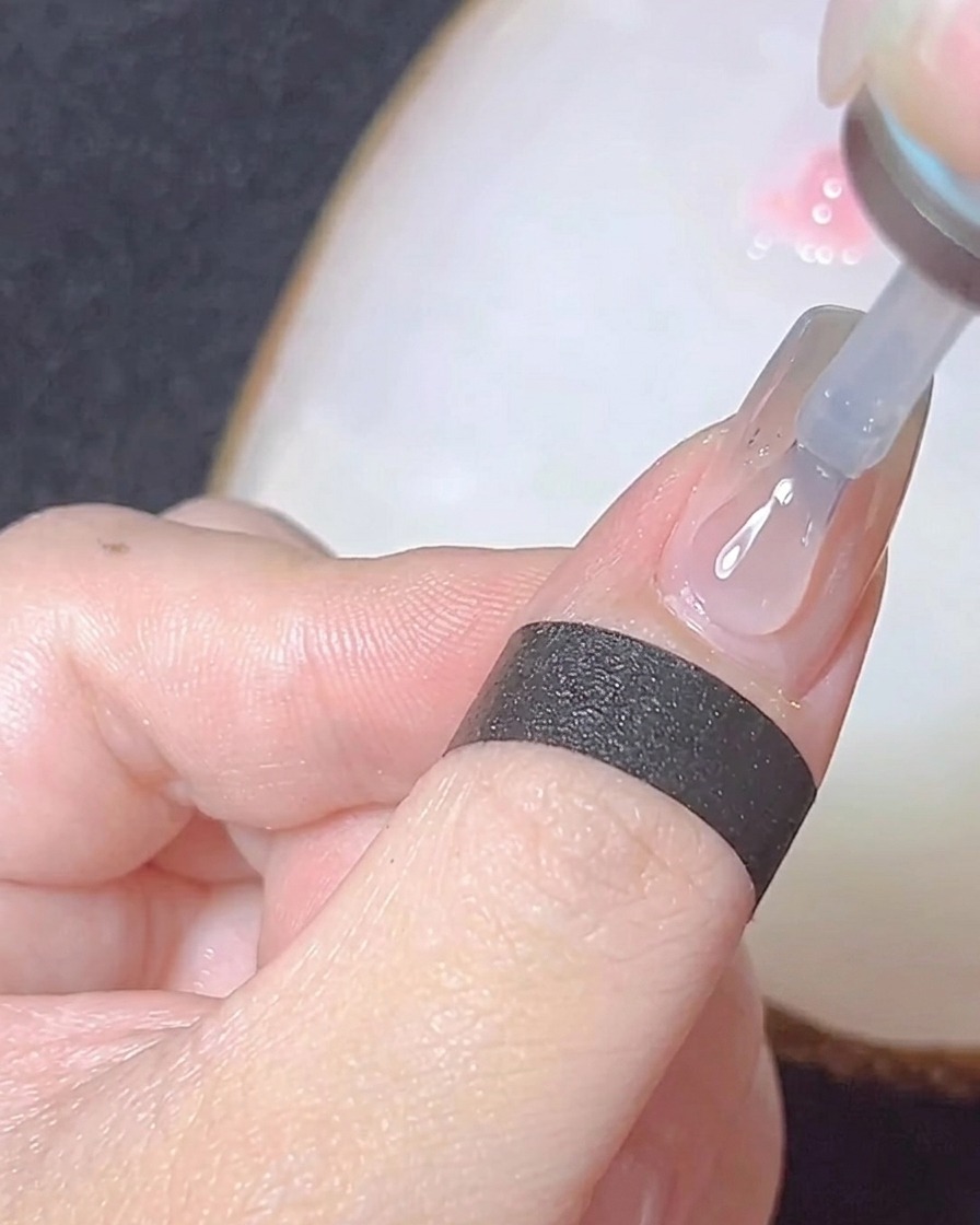 Nahaufnahme eines Pinsels, der einen glänzenden, klaren Top Coat über einen Chrome-Nagel aufträgt.