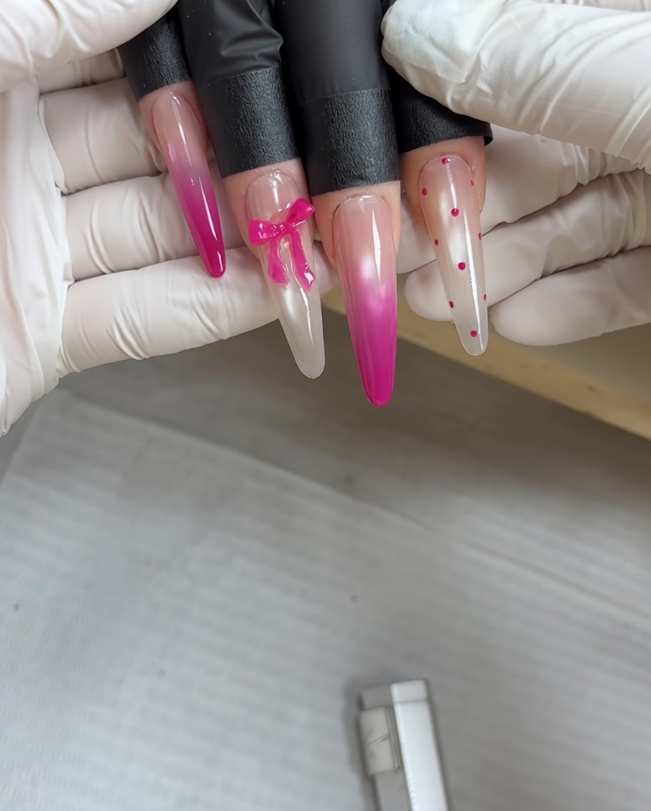 Ein Punktierwerkzeug trägt winzige rosa Punkte auf eine ausgehärtete, metallisch-graue Nageloberfläche auf.