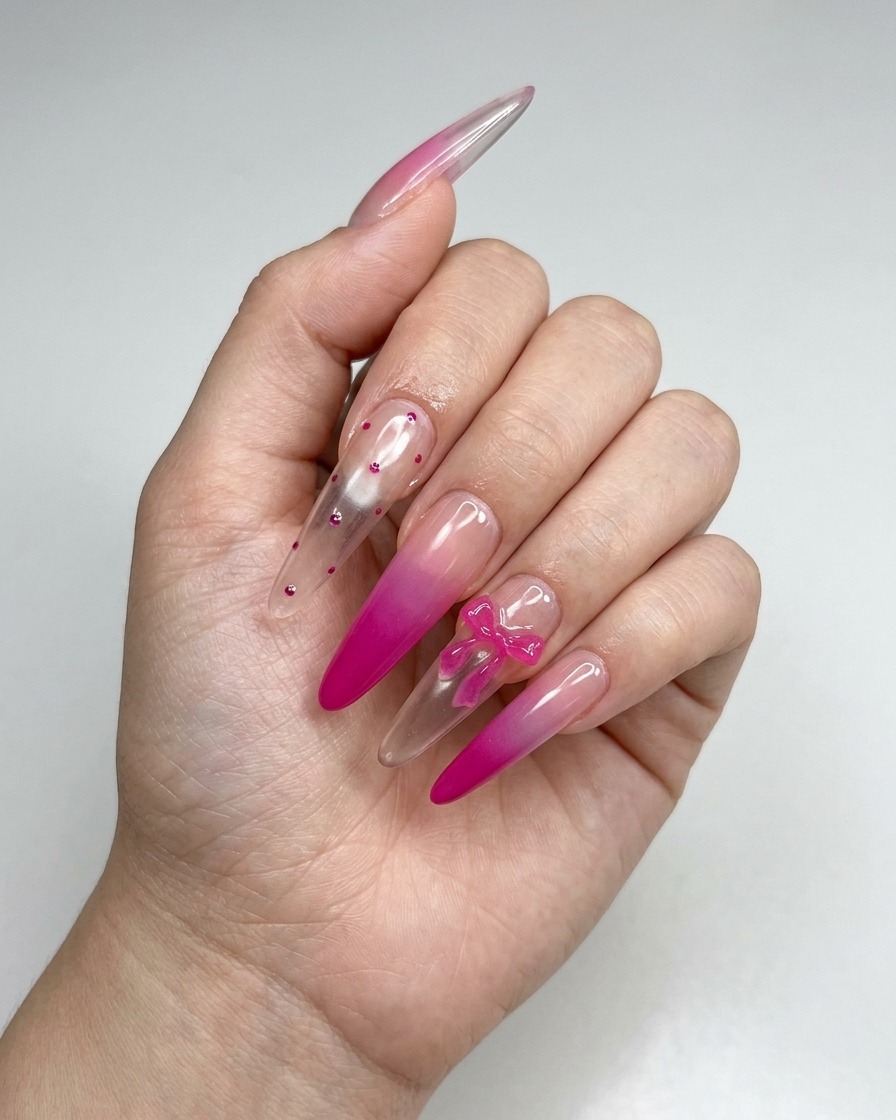 Eine Pinzette platziert einen kleinen 3D-rosa Schleifen-Charm auf der Oberfläche eines manikürten Nagels.