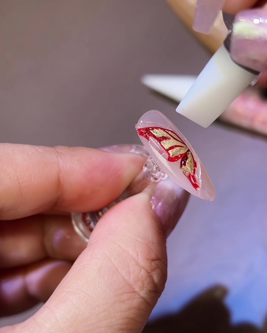 Ein Silikonwerkzeug formt das 3D-Gel in eine Schmetterlingsflügel-Silhouette auf dem Nagel.