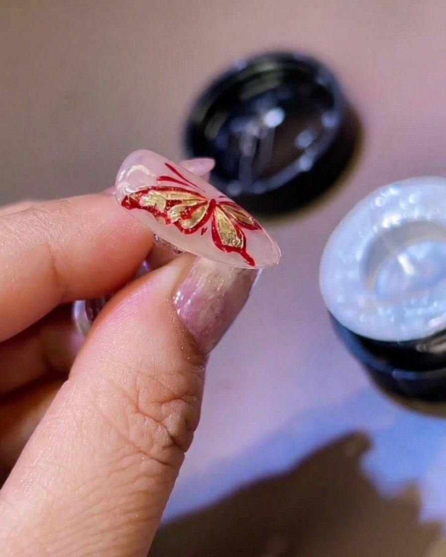 Ein feiner Liner-Pinsel setzt dünne weiße Gel-Details an die Kanten der 3D-Schmetterlingsflügel.