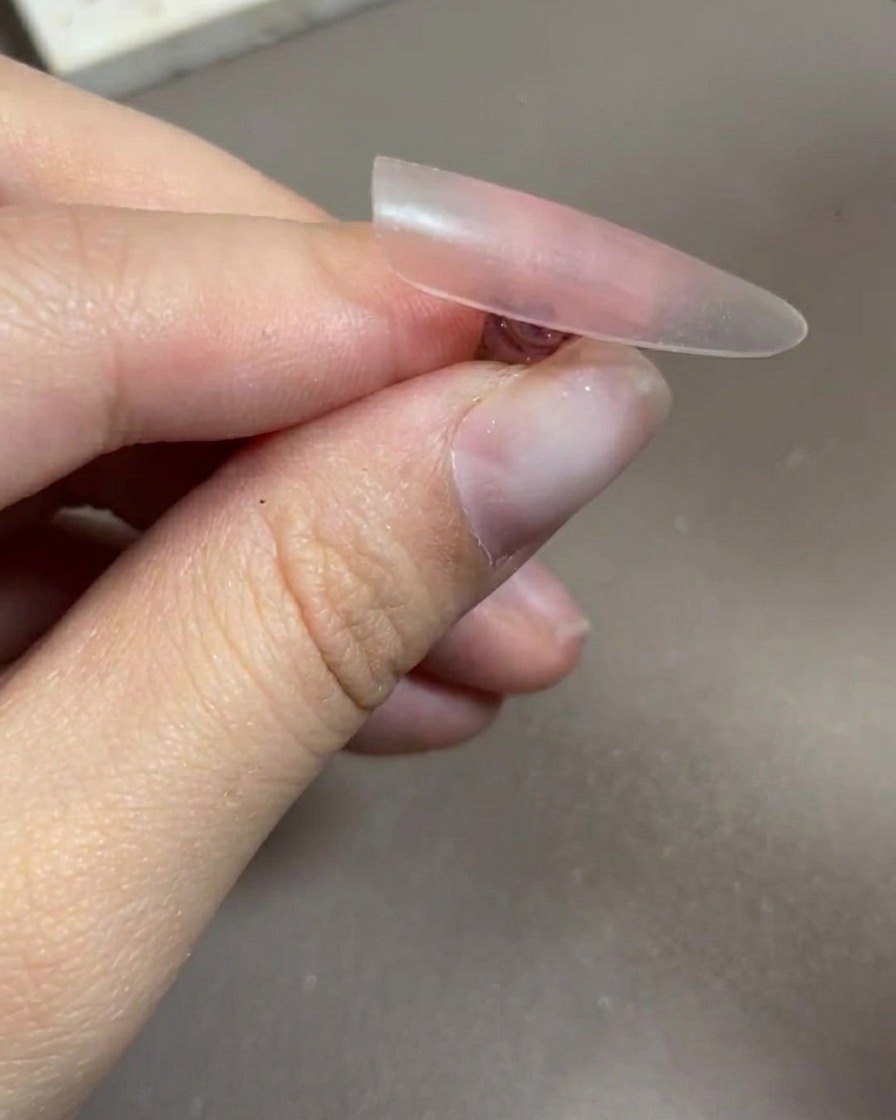 Eine Hand liegt in einer professionellen UV/LED-Nagellampe, die Nägel sind unter dem Licht deutlich sichtbar.