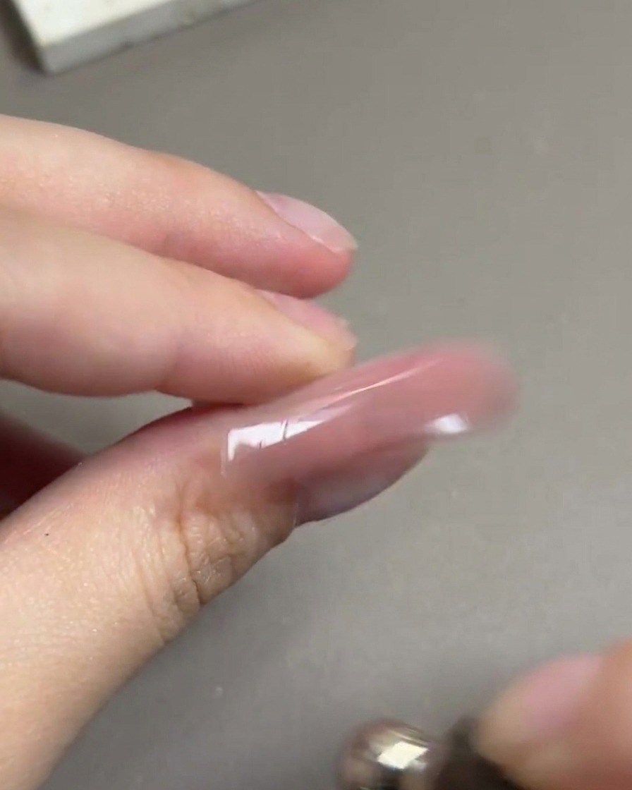 Ein Magnetwerkzeug wird in einer kreisenden Bewegung um einen Nagel geführt, um ein leuchtendes, kugelförmiges Highlight zu formen.