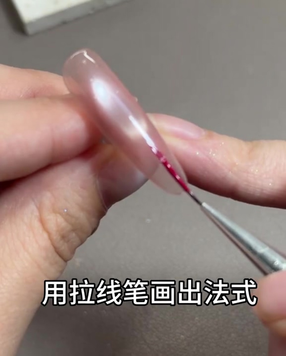 Ein dünner Nailart-Linerpinsel zieht eine zarte rosenrote Linie entlang der freien Nagelkante.