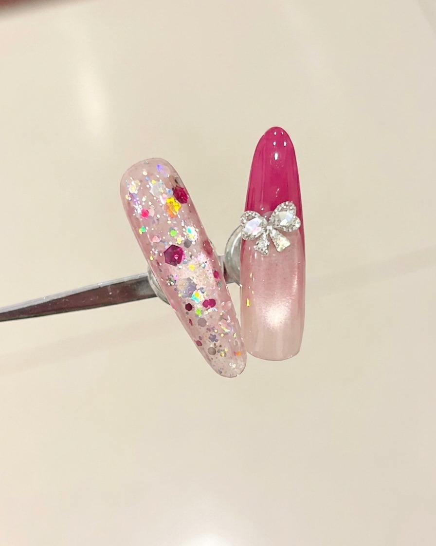 Ein Pinsel trägt einen klaren Überlack auf einen Nagel mit rosenroter French-Spitze auf.