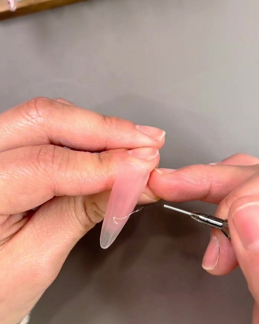 Detailansicht eines Liner-Pinsels, der goldenes Cat-Eye-Gel im French-Design aufträgt.