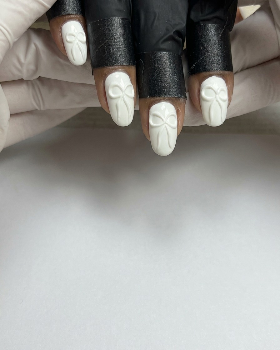 Ein Nagelpinsel trägt eine glatte Schicht weißes Gel auf einen vorbereiteten Naturnagel auf.