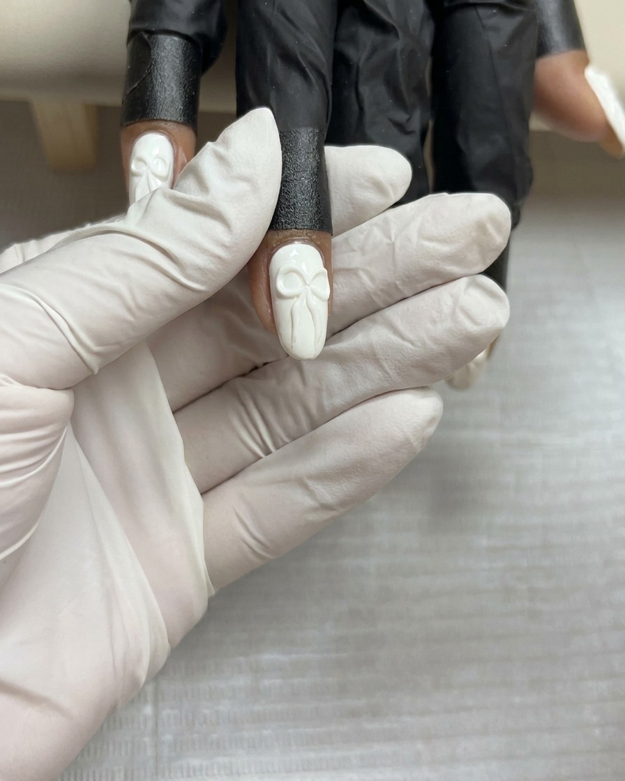 Eine Draufsicht auf ein fertiges 3D-Gelschleifen-Design auf einem weißen Nagel, das vor dem finalen Aushärten ruhig gehalten wird.