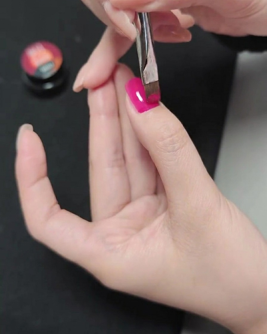 Ein Pinsel trägt eine zweite Schicht Magenta-Gel über die bereits gehärtete Schicht auf.
