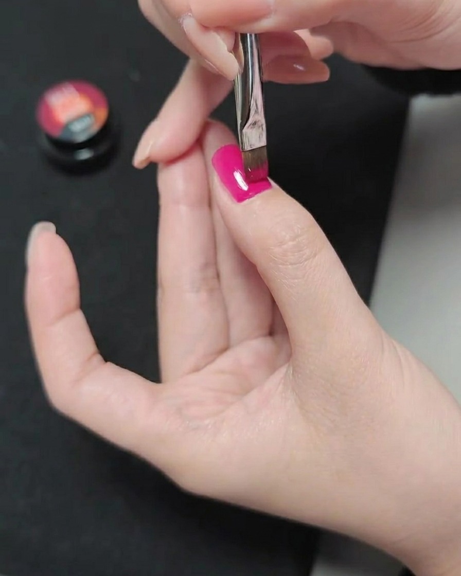 Ein Pinsel trägt eine dritte Schicht Magenta-Gel auf, was ein glattes und gesättigtes Farbergebnis erzeugt.