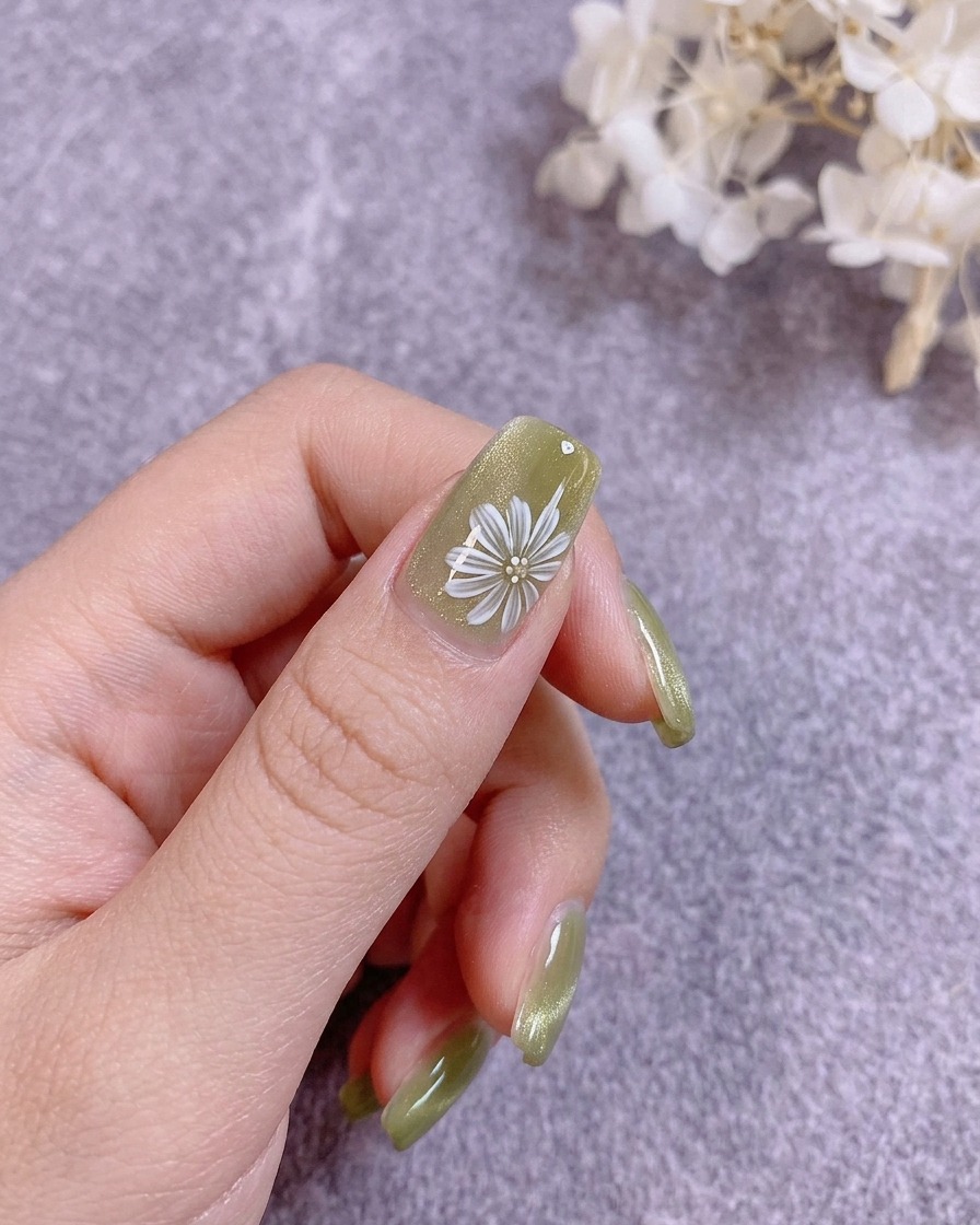 Ein Nagelpinsel trägt einen klaren Hard Top Coat über das florale Design auf.