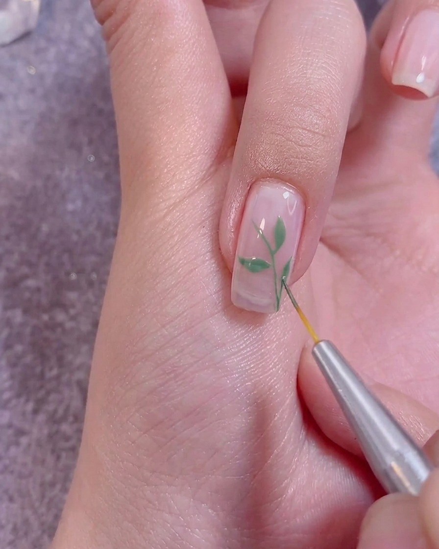 Auftragen eines klaren Top Coats über das fertige Nageldesign mit einem Profi-Nagelpinsel.