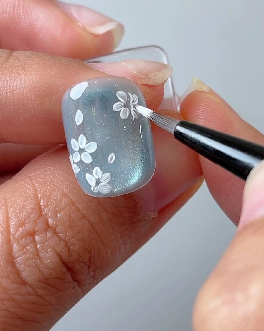 Ein Liner-Pinsel fügt einen neuen Blumen-Cluster an einer leeren Stelle des Nagels hinzu.