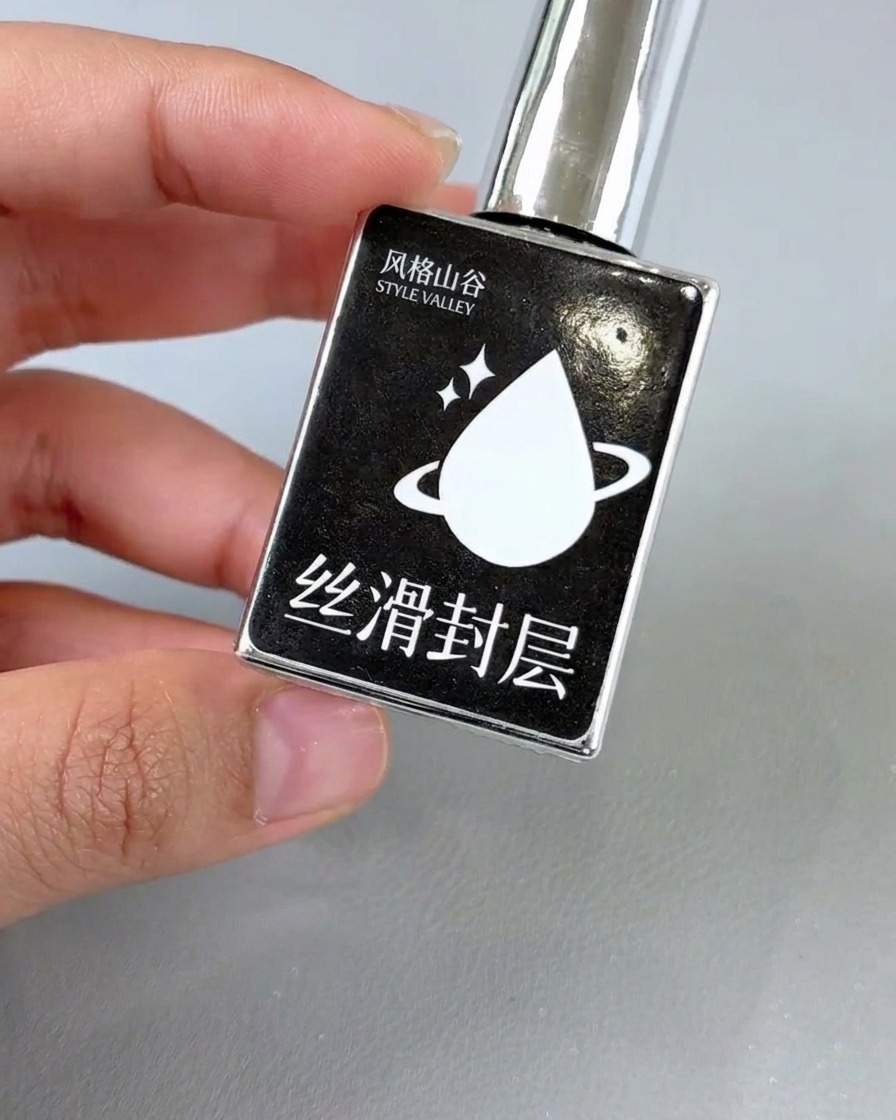 Ein Nagellackpinsel trägt klaren, glänzenden Top Coat auf ein fertiges florales Nageldesign auf.