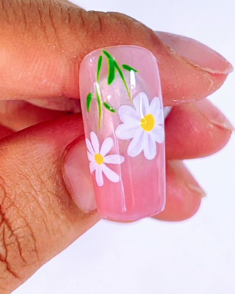 Ansicht des Nageldesigns mit dem zweiten Gänseblümchen und einem leuchtend gelben Mittelpunkt, bereit für die finale Härtung.