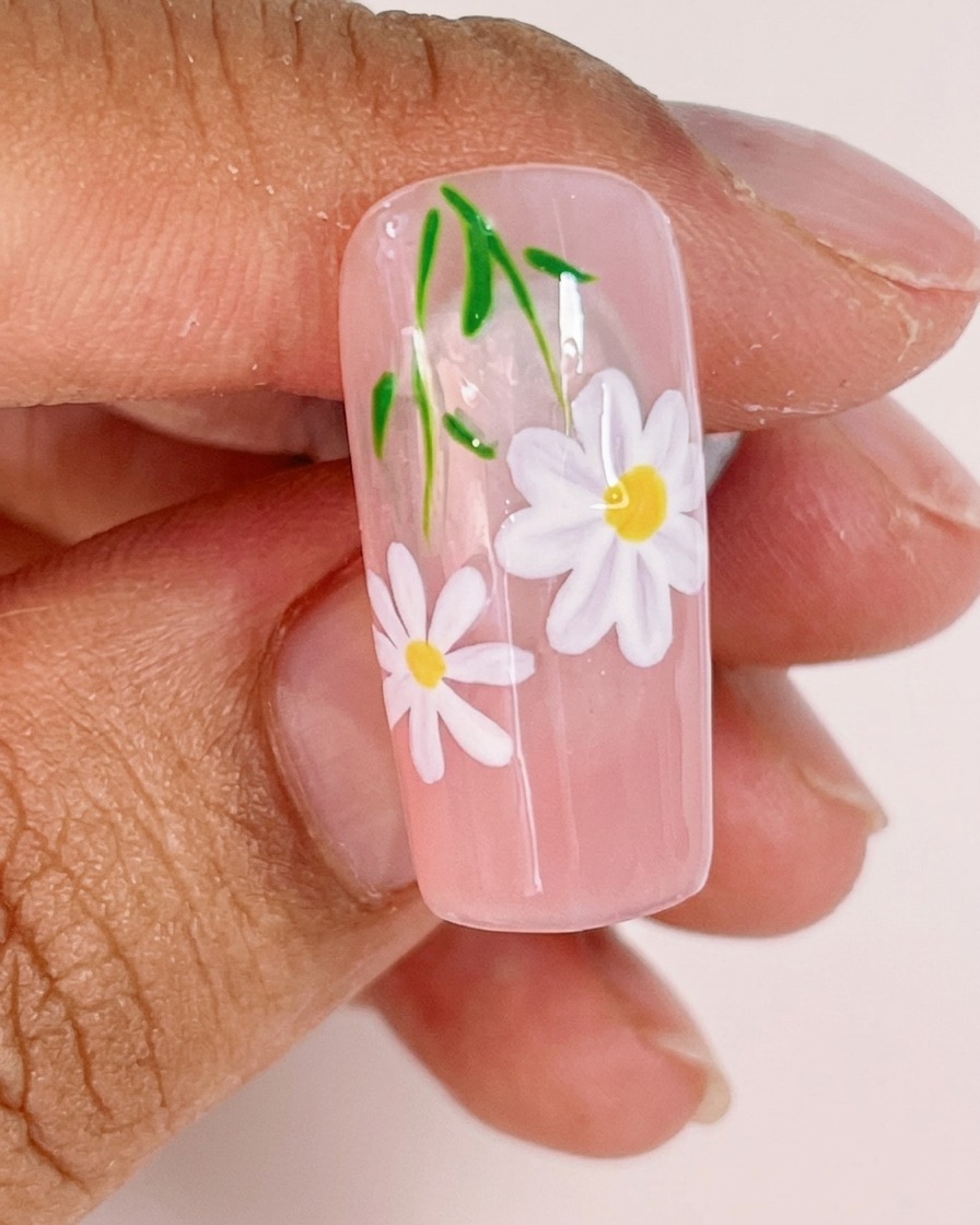 Nahaufnahme, wie ein feiner Liner-Pinsel zarte grüne Stiele und kleine Blätter zum Nageldesign hinzufügt.
