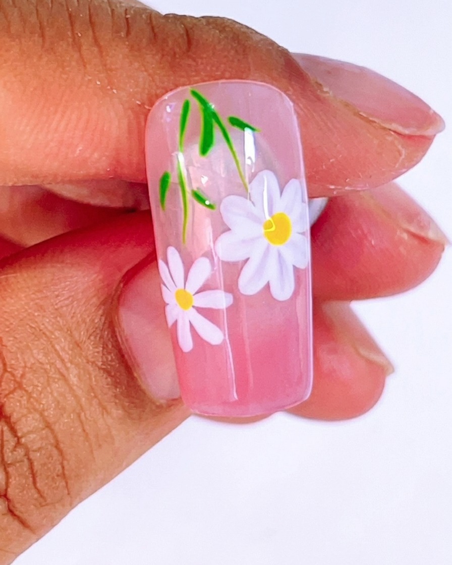 Ein Pinsel trägt eine großzügige Schicht klaren, glänzenden Top Coat über das fertige Blumen- und Blattdesign auf.