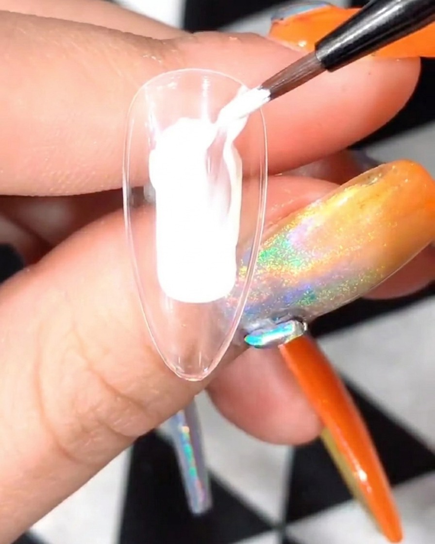 Ein klarer Nagel-Tip mit weißem Blütenblatt-Design wird unter einer UV/LED-Nagellampe ausgehärtet.