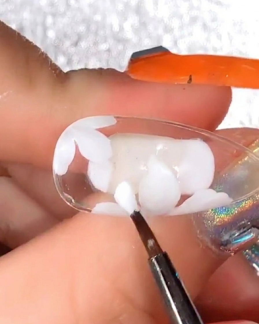 Detailpinsel fügt mehr weiße Gel-Blütenblätter über das bereits ausgehärtete Design hinzu, um das Volumen des Gänseblümchens zu erhöhen.