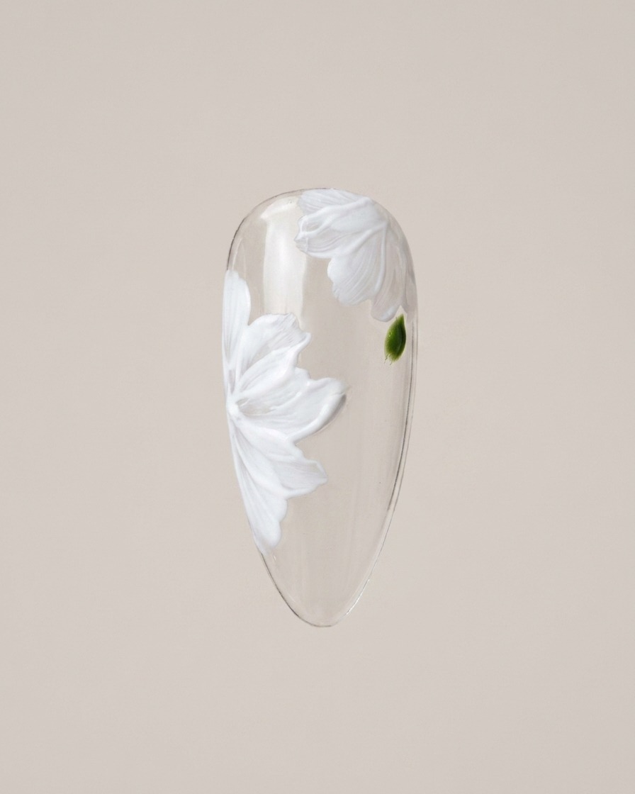 Ein Detailpinsel malt vorsichtig kleine grüne Blatt-Akzente in die Lücken zwischen den Gänseblümchen-Blütenblättern.