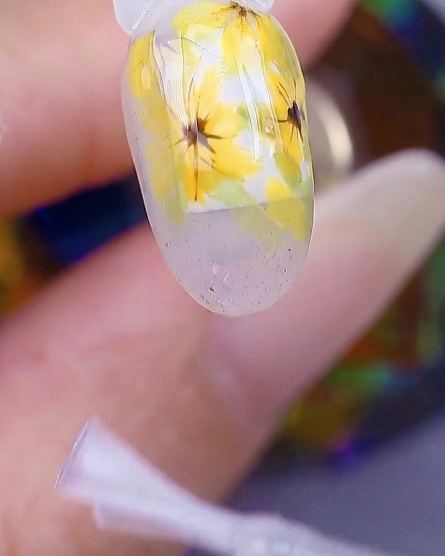 Nahaufnahme einer Hand in einer UV/LED-Nagellampe, wobei die Nageloberfläche unter dem Licht glänzend und feucht aussieht.