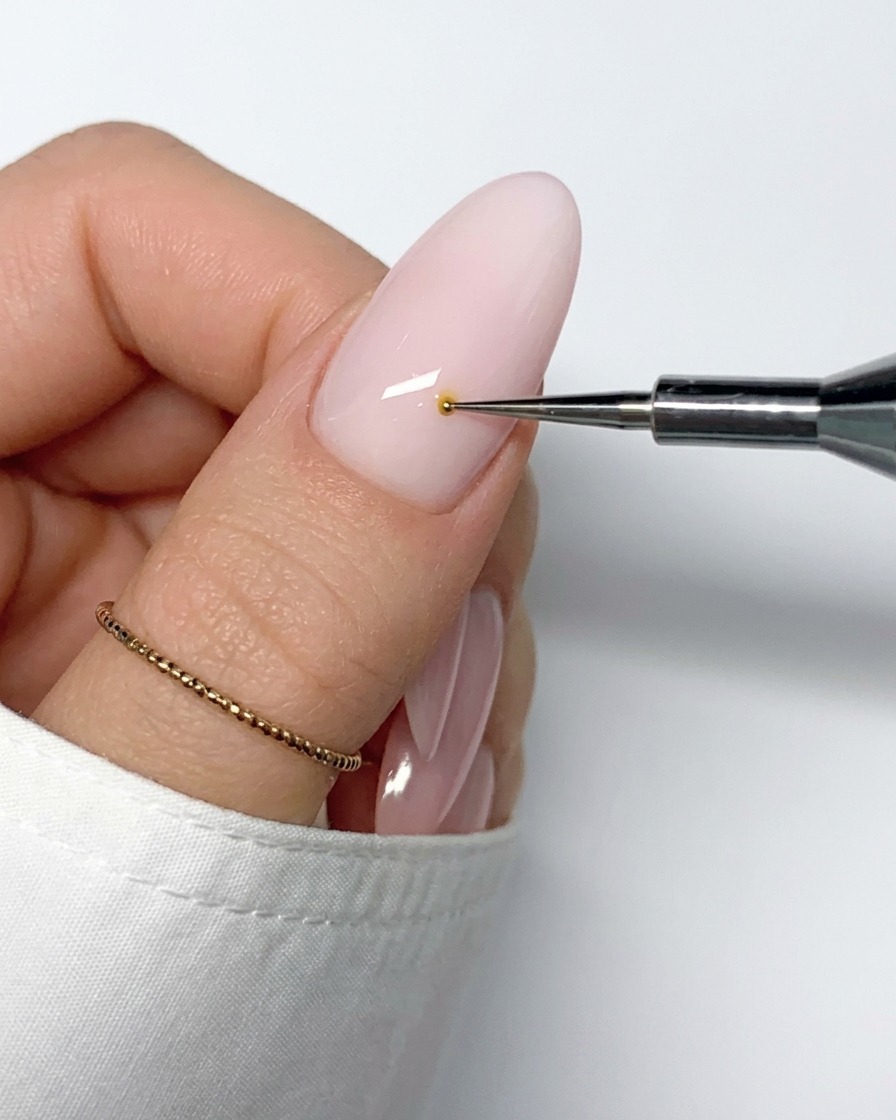 Ein feiner Nail-Art-Pinsel zieht eine weiße Gellinie vom gelben Zentrum nach außen.
