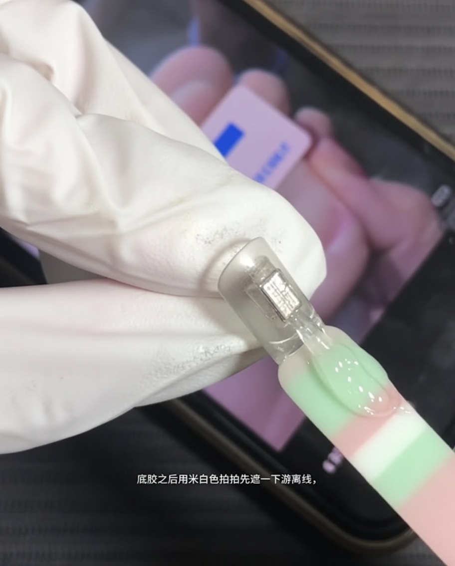 Ein Pinsel trägt milchig-weißes Gel auf die freie Kante eines Naturnagels auf.