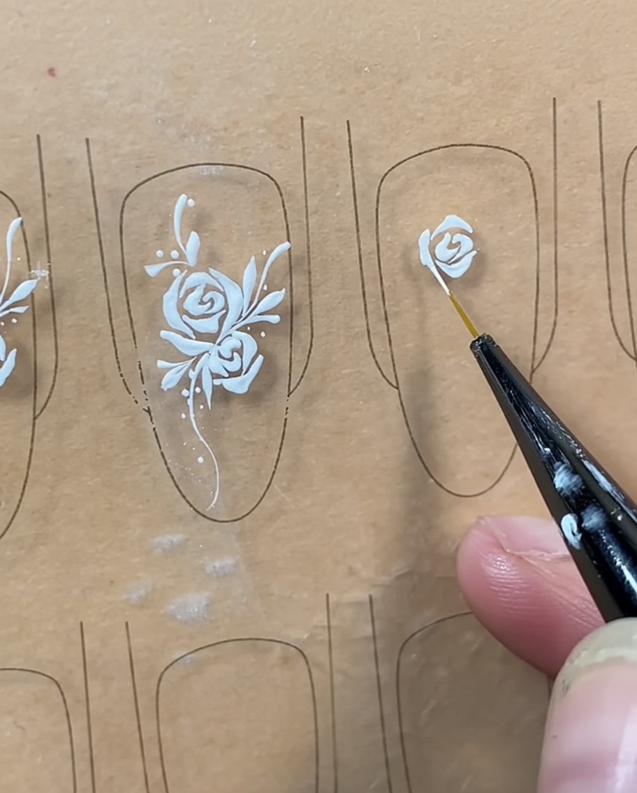 Ein Liner-Pinsel zeichnet eine geschwungene Linie unterhalb der Knospe, um die Rosenform zu schließen.