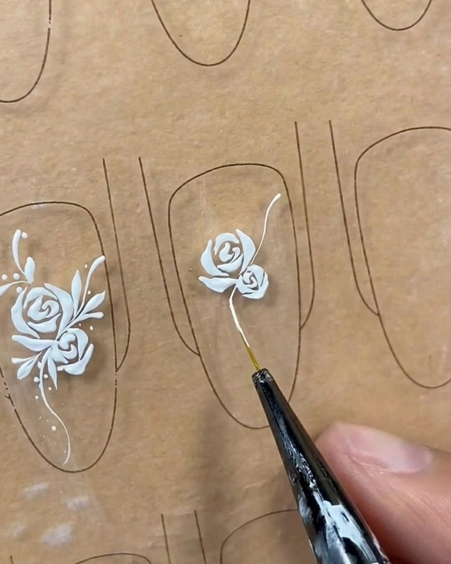 Eine lange, geschwungene weiße Rankenlinie wird mit einem Liner-Pinsel von der Basis der Rose aus gezeichnet.