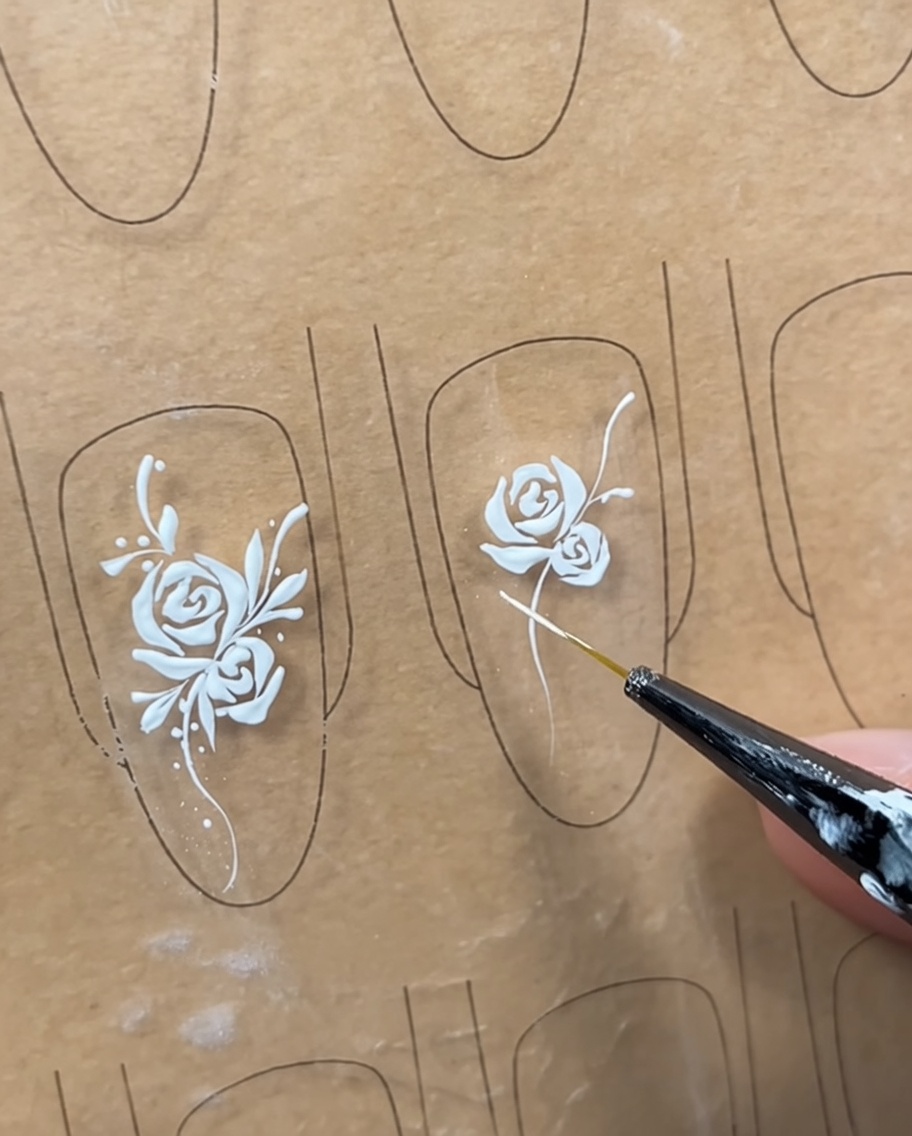 Ein Nageldesign mit Rose und Ranke, bei dem erste strukturelle Linien die Positionen der Blätter markieren.