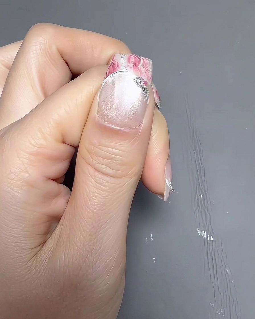 Ein Pinsel trägt eine ebenmäßige Schicht deckenden weißen Nagellacks auf einen Naturnagel auf.