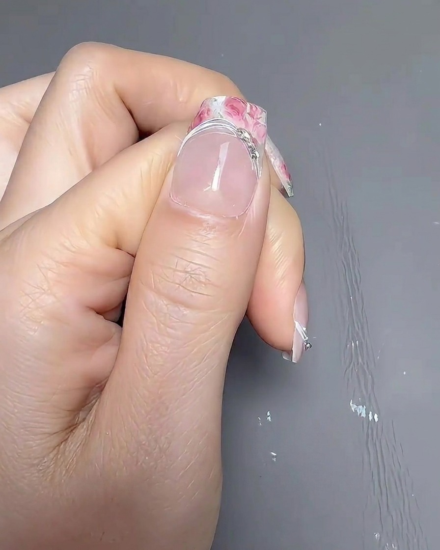 Eine Hand ruht in einer professionellen UV/LED-Nagellampe, während diese leuchtet.