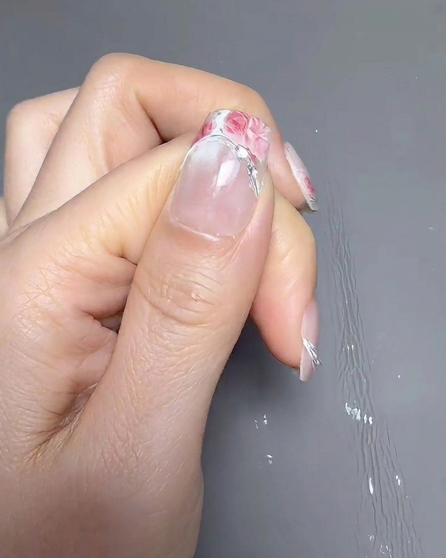 Eine Pinzette platziert einen French-Tip-Aufkleber etwas höher auf dem Nagel.