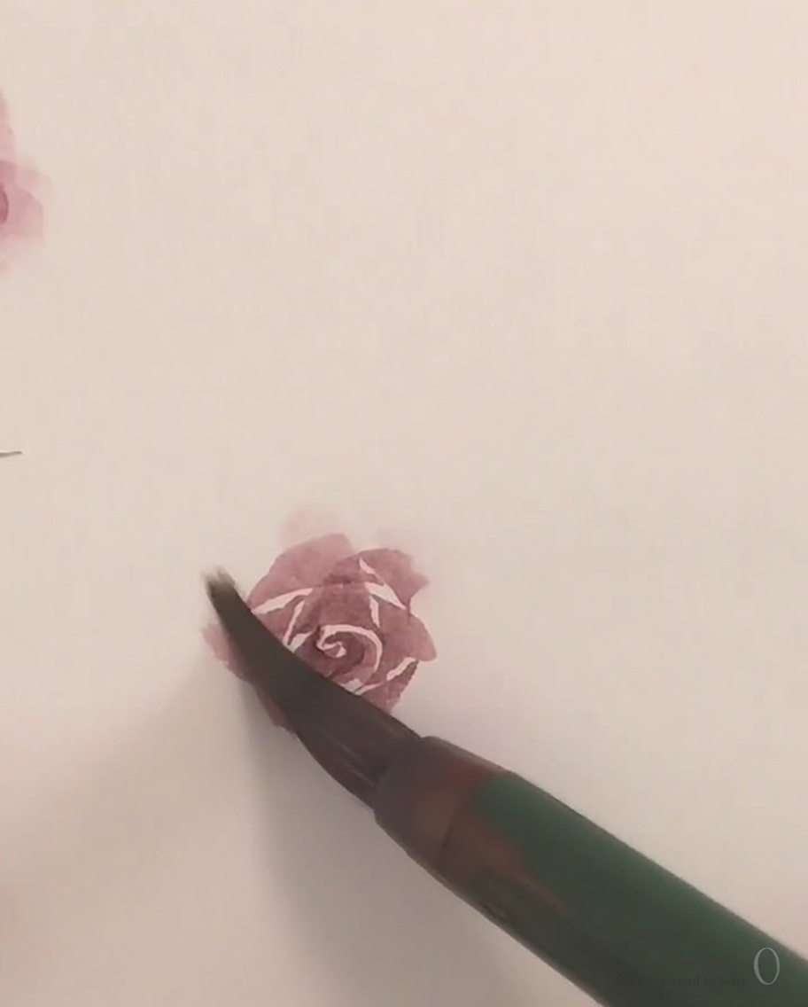 Ein kleiner Pinsel trägt zarte rosa Aquarellfarbe auf, um das letzte äußere Blütenblatt einer Rose zu formen.