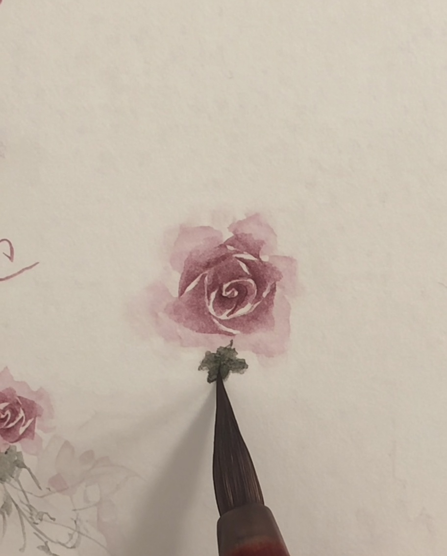 Ein sauberer Pinsel verblendet leicht die Kanten einer rosa Aquarell-Rose.