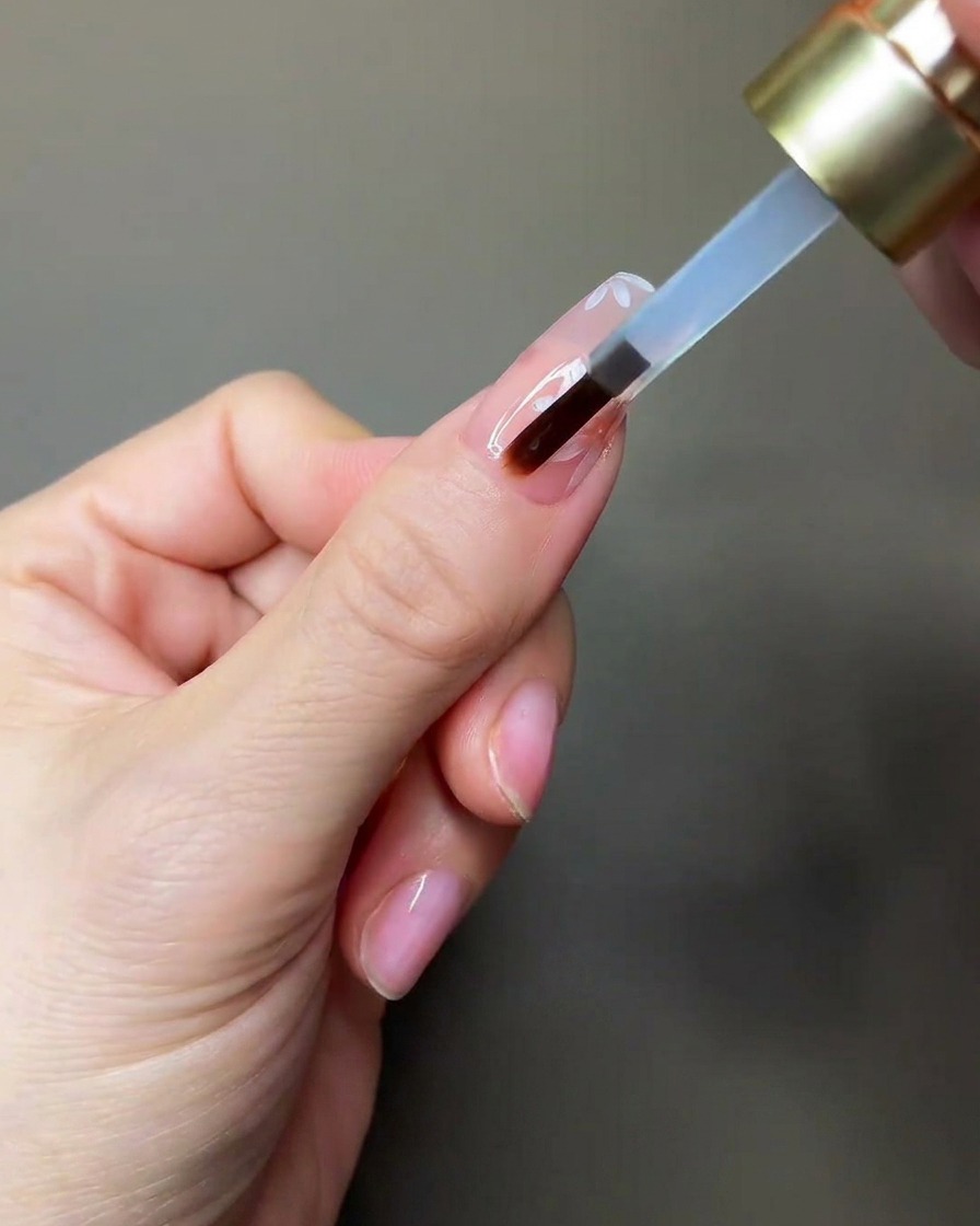 Eine Hand legt einen Nagel unter eine kleine tragbare UV/LED-Lampe zum Aushärten.