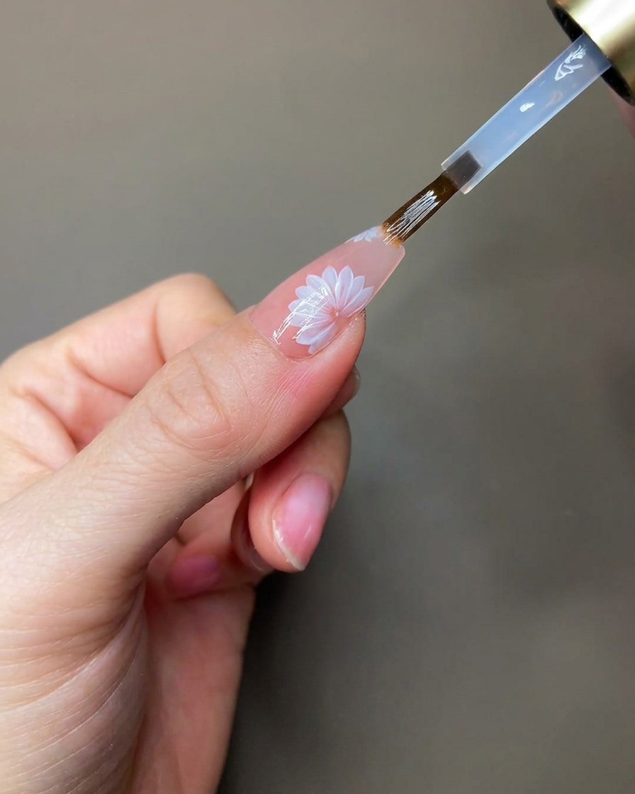 Eine Hand wird unter eine tragbare UV/LED-Lampe gehalten, während die klaren Modelliergel-Details aushärten.