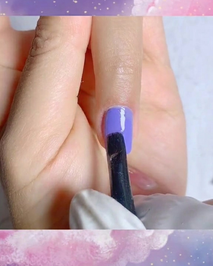 Eine Nahaufnahme eines feinen Liner-Pinsels, der präzise weiße Blütenblattstriche auf einen violetten Geluntergrund zeichnet.