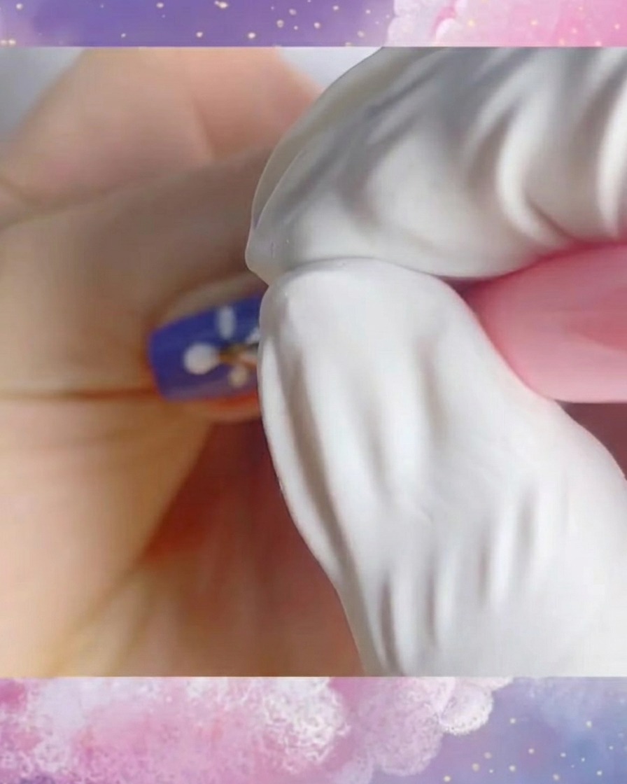 Eine Nahaufnahme eines fertigen weißen Gänseblümchen-Designs auf einem violetten Nagel, erstellt mit dünnen, sauberen Strichen.
