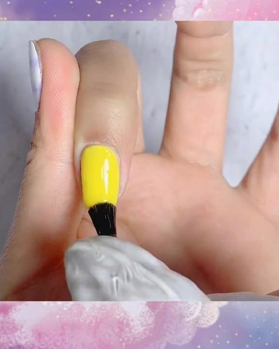 Ein Pinsel trägt matten Überlack auf einen Fingernagel mit handgemaltem blau-weißem Karodesign auf.