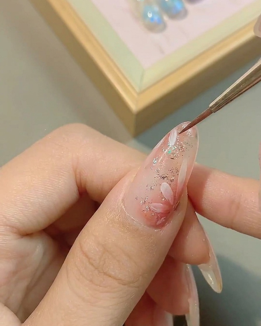 Ein Pinsel trägt glänzenden Top Coat auf das Gänseblümchen-Design auf.