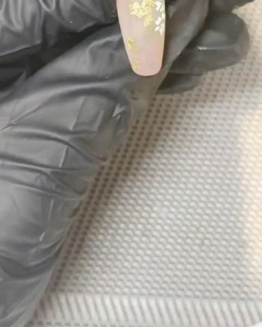 Ein kleiner Pinsel tupft gelbes Gel in die Mitte eines weißen gemalten Gänseblümchens.