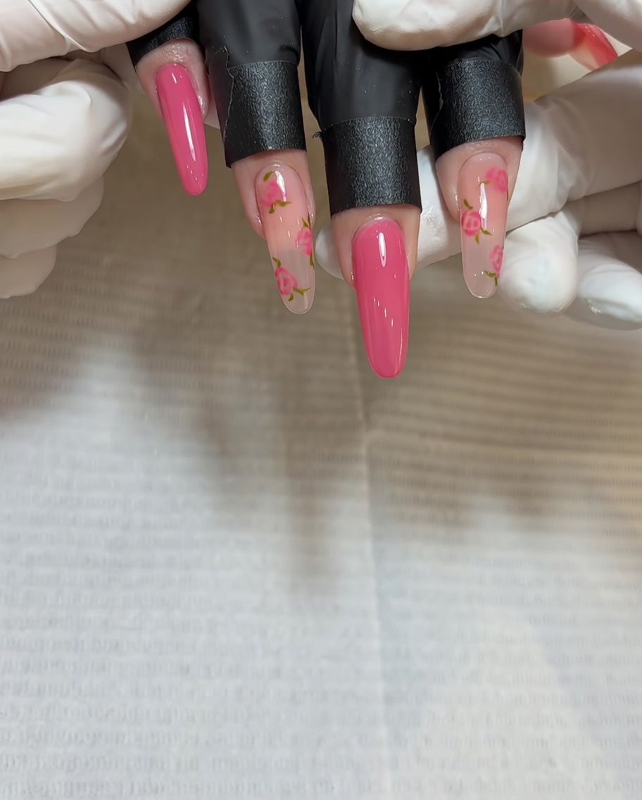 Nahaufnahme eines Pinsels, der dunkles Rot in die Mitte des zweiten Rosen-Clusters auf dem Nagel aufträgt.